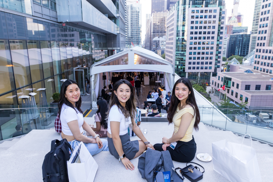 three women looking at the camera with the city of Toronto in the background