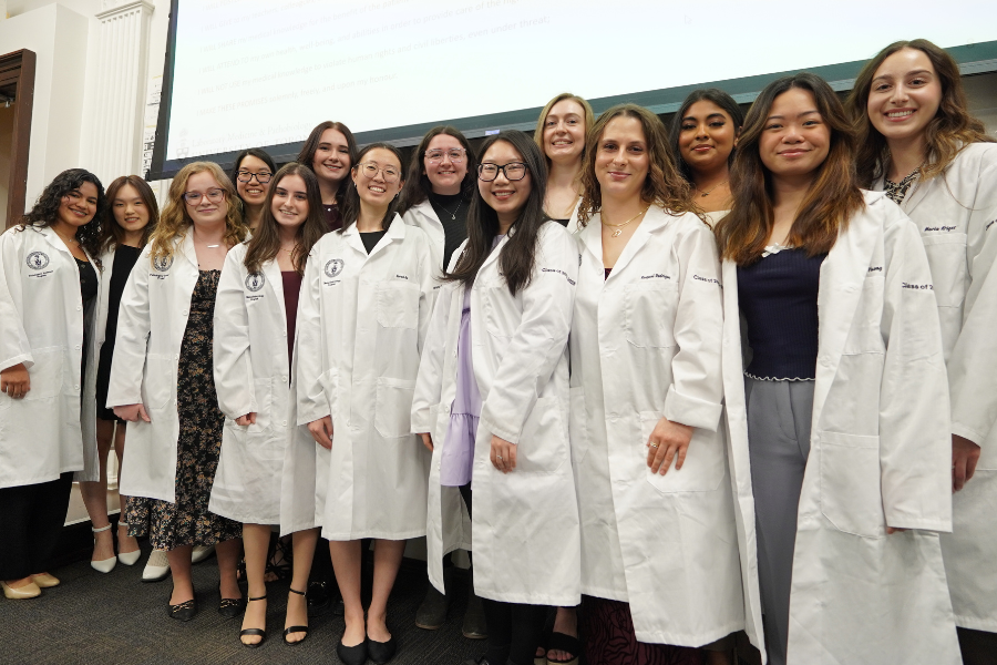 A group of people in white laboratory coats smiling at the camera