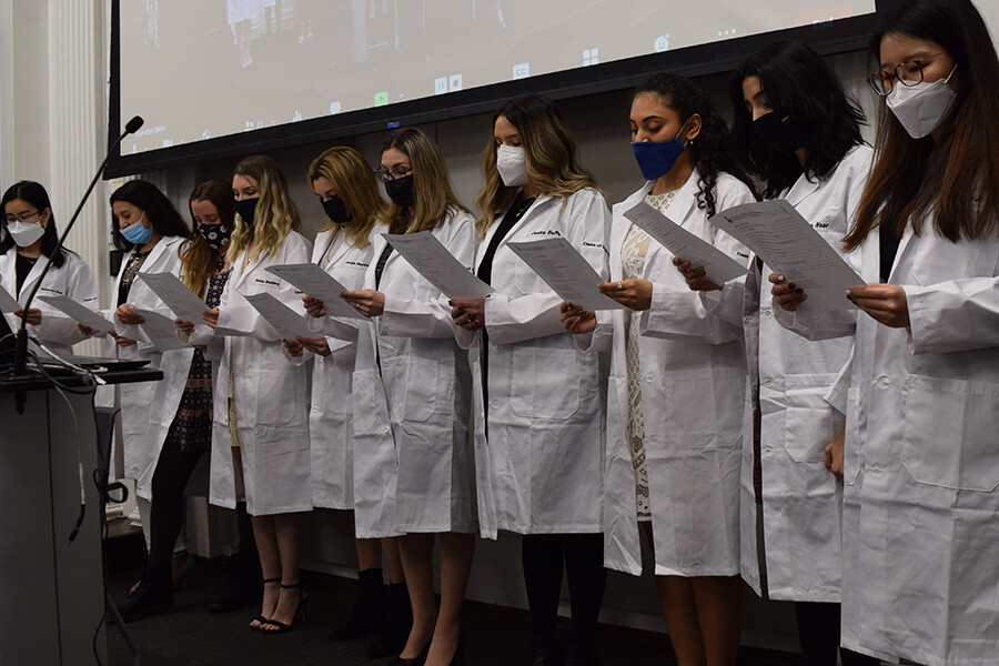 A group of people in white coats reading